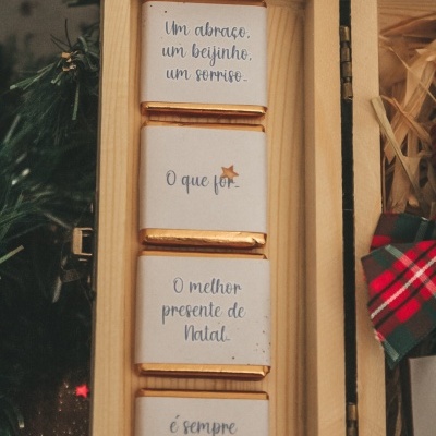 Quatro chocolates com mensagens de Natal em caixa de madeira aberta