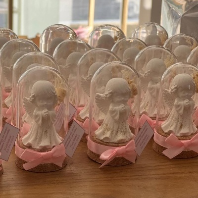 Miniaturas de anjos brancos em domos de vidro com base de cortiça e fitas rosas