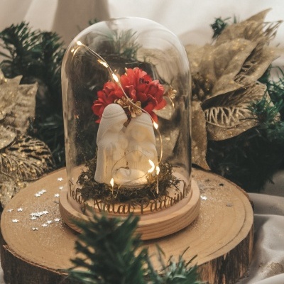 Anjo branco em cúpula de vidro com flores vermelhas e luzes, em base de madeira