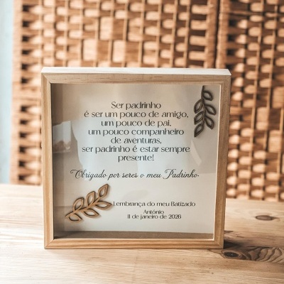 Placa decorativa emoldurada em madeira clara com texto em português e ornamentos em forma de folhas, sobre mesa de madeira clara