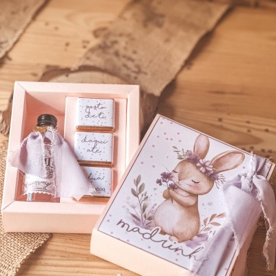 Caixa de presente com garrafa e chocolates, com ilustração de coelho e texto em português