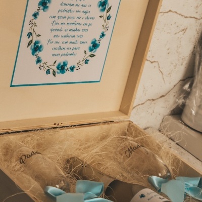 Caixa de madeira com dois copos de vidro inscritos e papel decorativo azul no interior da tampa