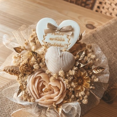 Bouquet decorativo com flores artificiais bege, detalhes dourados e corações com texto em cerâmica.