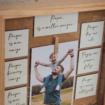 Moldura de madeira e cortiça com foto de pai e filho e cartões com texto em português