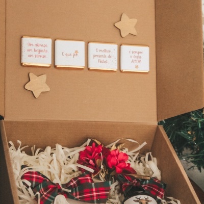 Caixa de presente com decorações natalícias e frasco com etiqueta 'Feliz Natal'