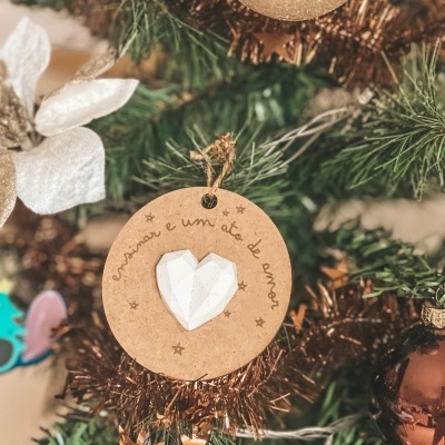 Ornamento de madeira redondo com coração branco pendurado em árvore de Natal verde decorada