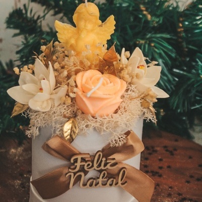 Vela decorativa de Natal com laço castanho, anjo de cera amarelo e flores artificiais na tampa