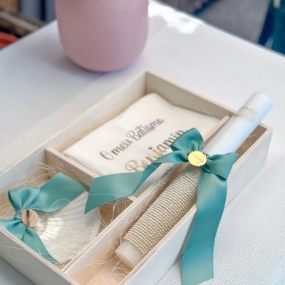 Caixa de madeira com vela decorada, concha e pano para batismo com texto impresso