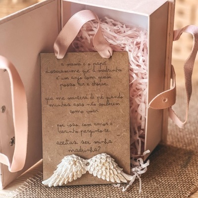 Caixa rosa com cartão e asas decorativas brancas em papel castanho