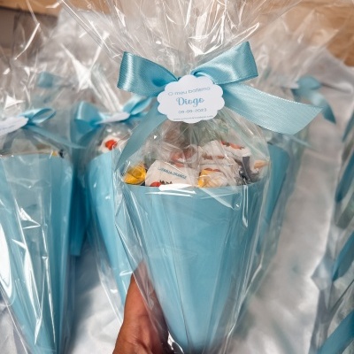 Cone azul com doces e etiqueta para batizado embalado em plástico transparente