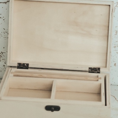 Caixa de madeira clara aberta com compartimentos internos