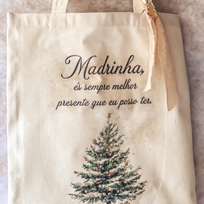 Saco bege de tecido com desenho de árvore de Natal e texto em português.