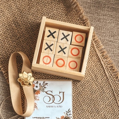 Jogo da velha em blocos de madeira com cartão personalizado de casamento sobre tecidos de juta e cinza