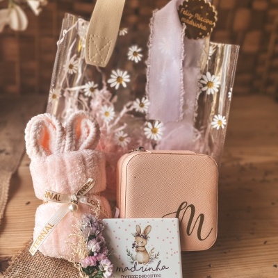 Conjunto de presente com bolsa transparente, toalha rosa com orelhas, estojo rosa e placa com coelho e texto para madrinha