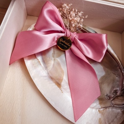 Prato decorativo oval com ramo de flores secas e laço rosa com etiqueta 'Gabriela Personalizados' em caixa de madeira