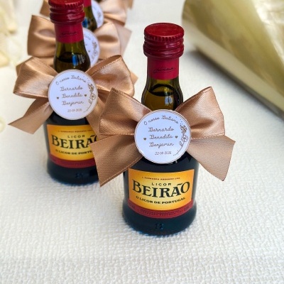 Mini garrafas de licor Beirão com laço bege e etiqueta personalizada para batismo