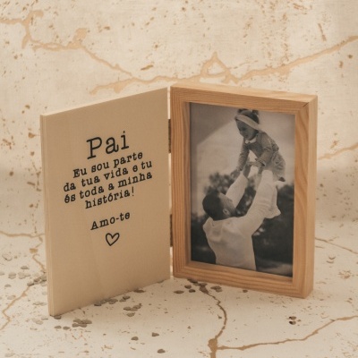 Objeto de madeira com foto em preto e branco de homem e criança e mensagem escrita em português