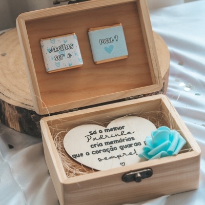 Caixa de madeira com quadros decorativos e coração com texto numa superfície de tecido branco