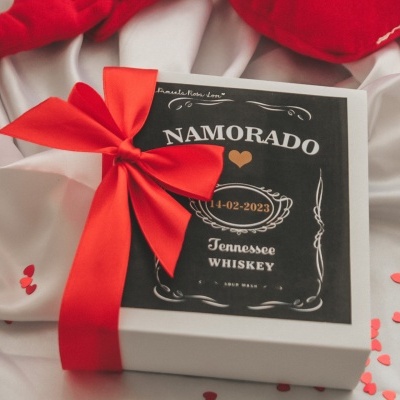 Caixa branca com tampa preta decorada, laço vermelho e confetes de coração