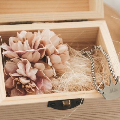 Caixa de madeira com flor decorativa rosa e colar prateado com pendente em forma de coroa