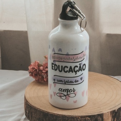 Garrafa desportiva branca com texto e detalhes em corações, sobre base de madeira