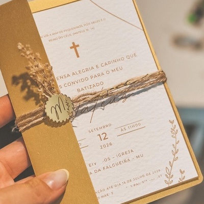 Convite de batizado com envelope dourado e decoração de flores secas