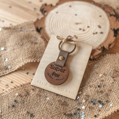 Porta-chaves de couro castanho com mensagem Super Pai em base de madeira clara decorada com juta e estrelas prateadas