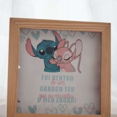 Quadro de madeira com ilustração de duas personagens animadas abraçadas e texto sentimental em português