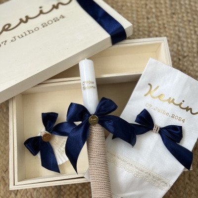 Conjunto de vela decorativa, pano branco com renda e caixa de madeira, todos com laço azul e texto Kevin 07 Julho 2024
