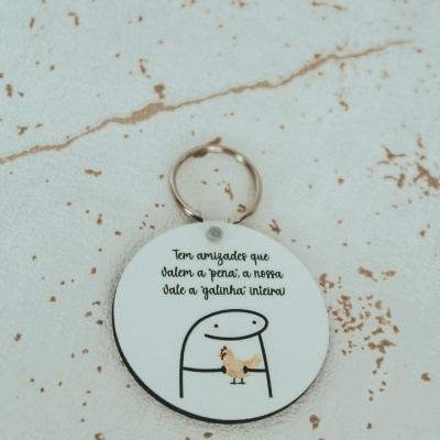Chaveiro branco com desenho de pessoa segurando galinha e texto em português