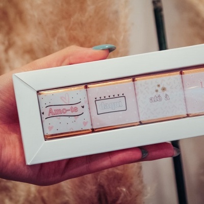 Caixa branca com quatro chocolates embalados individualmente com texto em português e desenhos coloridos