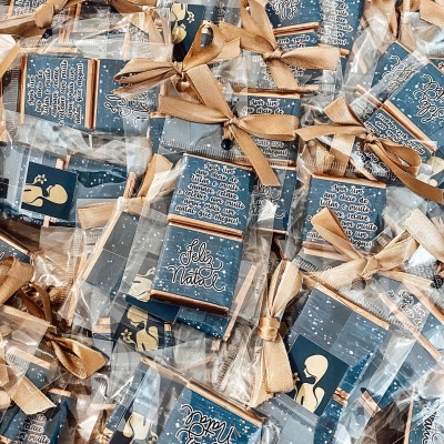 Pequenas caixas azuis de Natal com texto e laços dourados embaladas individualmente