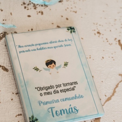 Caixa branca com desenho de anjo e texto sobre Primeira comunhão de Tomás
