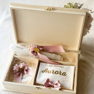 Caixa de madeira com itens para batismo decorados em tons rosa e branco.