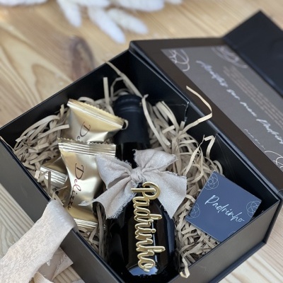 Caixa de presente preta com garrafa preta com decoração e chocolates dourados
