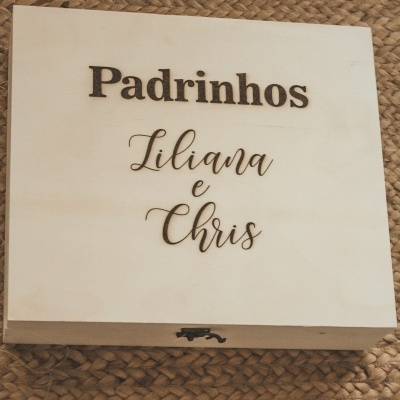 Caixa de madeira clara com texto 'Padrinhos Liliana e Chris'