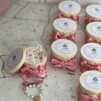 Caixas redondas de madeira com laço rosa, etiqueta decorativa e pulseira com cruz