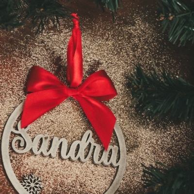 Enfeite de natal de madeira com o nome Sandra e laço vermelho pendurado em árvore de natal