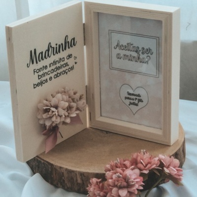 Caixa de madeira em formato de livro com texto e flores decorativas cor de rosa