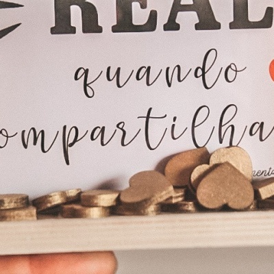 Moldura branca com texto em português e moedas douradas junto a corações de madeira