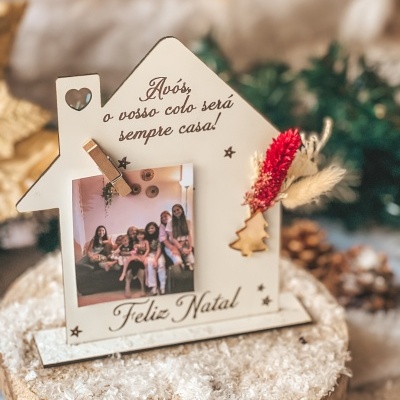Porta-fotos natalício em forma de casa com texto em português e decoração de flores secas.