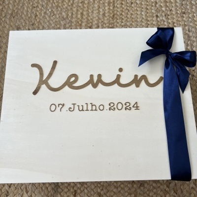 Caixa de madeira clara com nome Kevin e fita azul escura