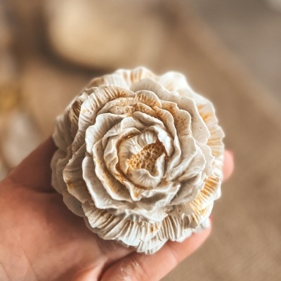 Escultura branca de flor detalhada em mão com fundo desfocado