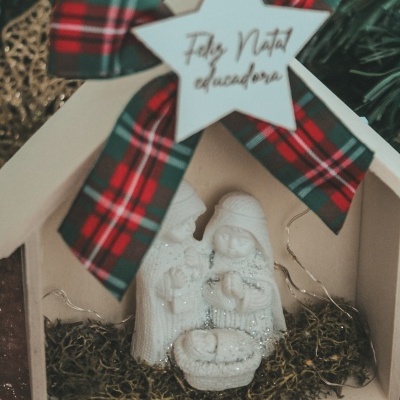 Presépio decorativo branco com figuras de resina, laço xadrez e estrela com texto de Natal