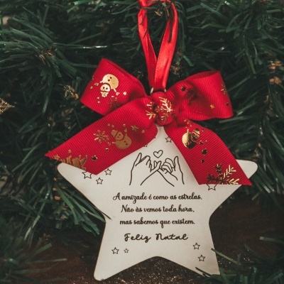 Estrela branca decorativa com laço vermelho e mensagem de Natal pendurada em pinheiro