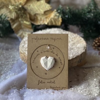 Cartão com coração branco e texto manuscrito em ambiente decorado para Natal.