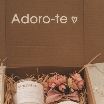 Caixa aberta com vela, sachê e laço decorativo com flores e texto 'Adoro-te ♡' na tampa