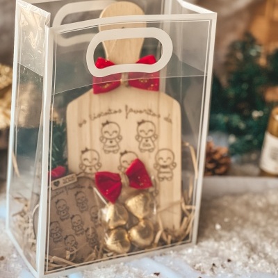 Conjunto de presente com tábua de madeira, chocolates e saco dentro de embalagem plástica transparente