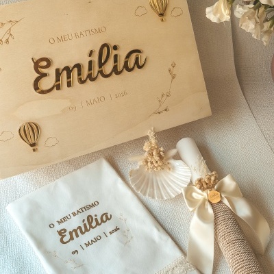 Conjunto de batismo branco com toalha, vela com laço e caixa de madeira decorada com nome Emilia.