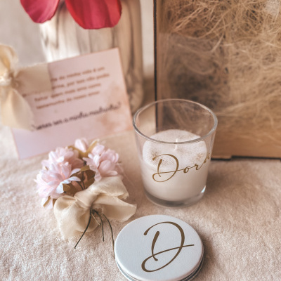 Vela em copo de vidro com flores artificiais e caixa decorativa em fundo claro